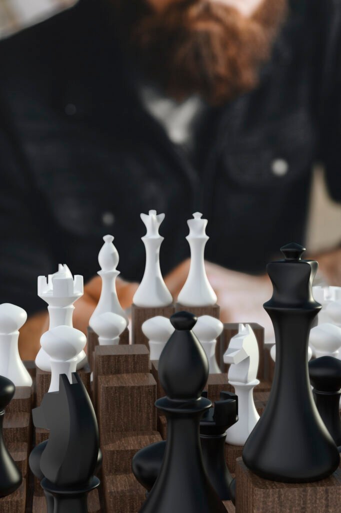 El juego completo de Ajedrez 4D con piezas blancas y negras de formas clásicas, cada una sobre su propio bloque de madera de distinta altura, con una persona sentada al fondo desenfocada.