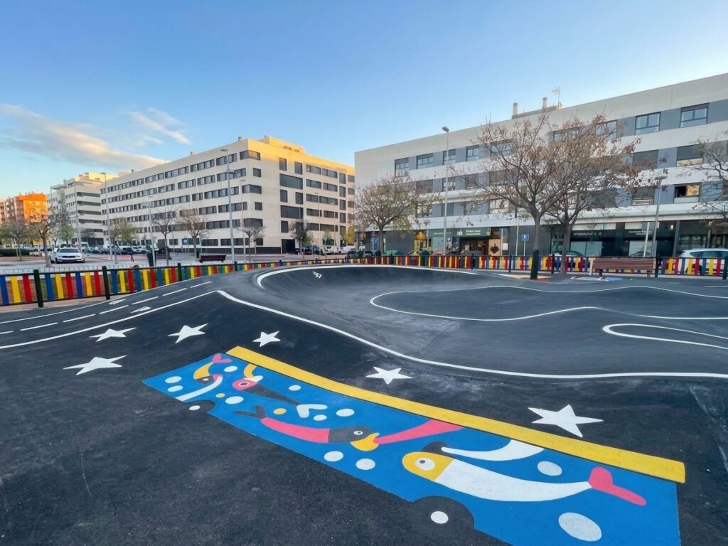 Vista del circuito con una curva pintada de azul con estrellas y, en primer plano, una ilustración de aves de colores sobre una franja azul con el borde amarillo.